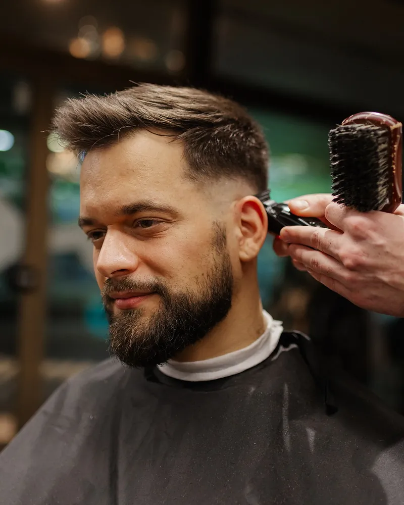 Barber using clippers on a men's taper cut at Robert's Salon and Spa in Belmont, MA